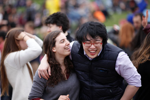 A couple embracing and laughing with other attendees in the background at the festival.