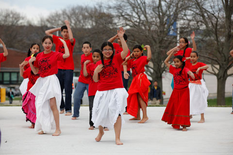 Young dancers in red “Latin American Cultural Family Network” tee shirts performing.