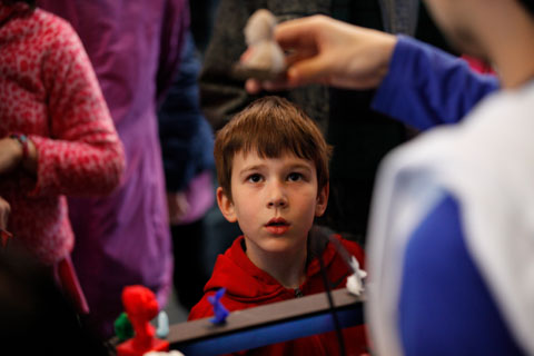 A boy staring at an item printed on the 3D printer.