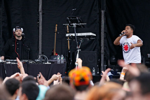 Performers on stage in front of a festival crowd.