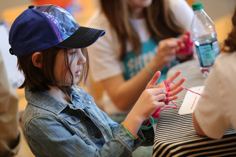 A child wraps yarn on her fingers