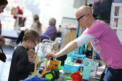 Ian Roy helps children use materials on the MakerLab table.