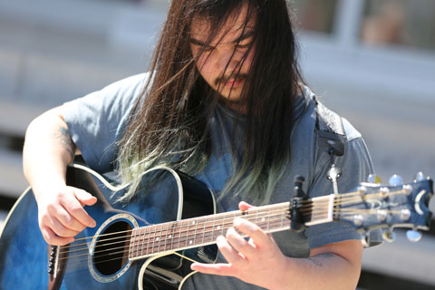 Eli Kengmana ’19 playing a blue sunburst acoustic guitar.