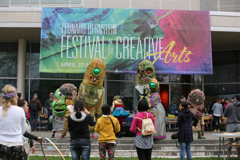 BIG NAZO, large monster-like costume, dance to live music by the Boycott band in front of the Festival of the Arts banner outside