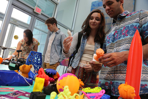 Students looking at items on a table made with a 3D printer