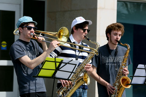 One trombonist and two saxophone players performing in front of the Shapiro Campus Center.
