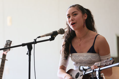 A performer singing and playing her ukulele.