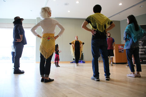 Participants of various ages with scarves in a circle, with hands on their hips.