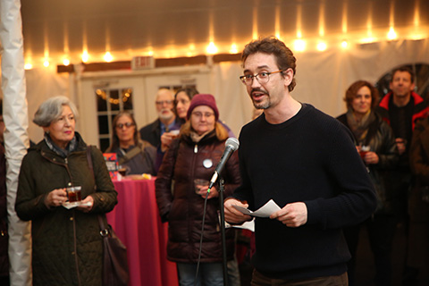 Man speaking into microphone with audience watching.