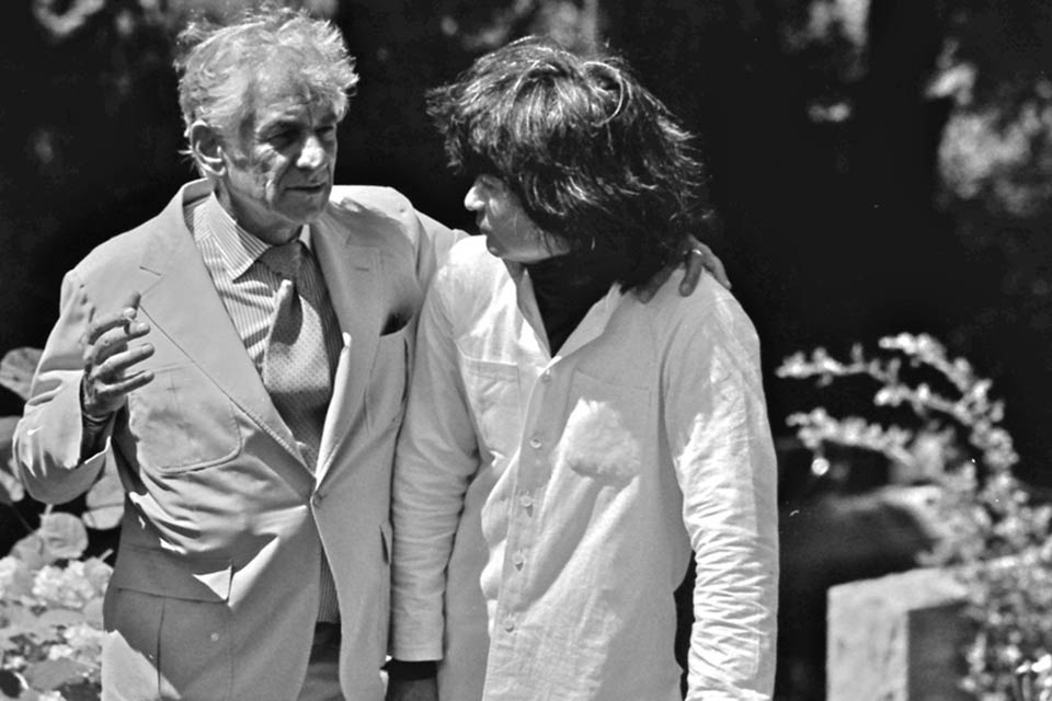 Leonard Bernstein with arm around Seiji Ozawa, while Ozawa leans on the grave marker of Koussevitzky