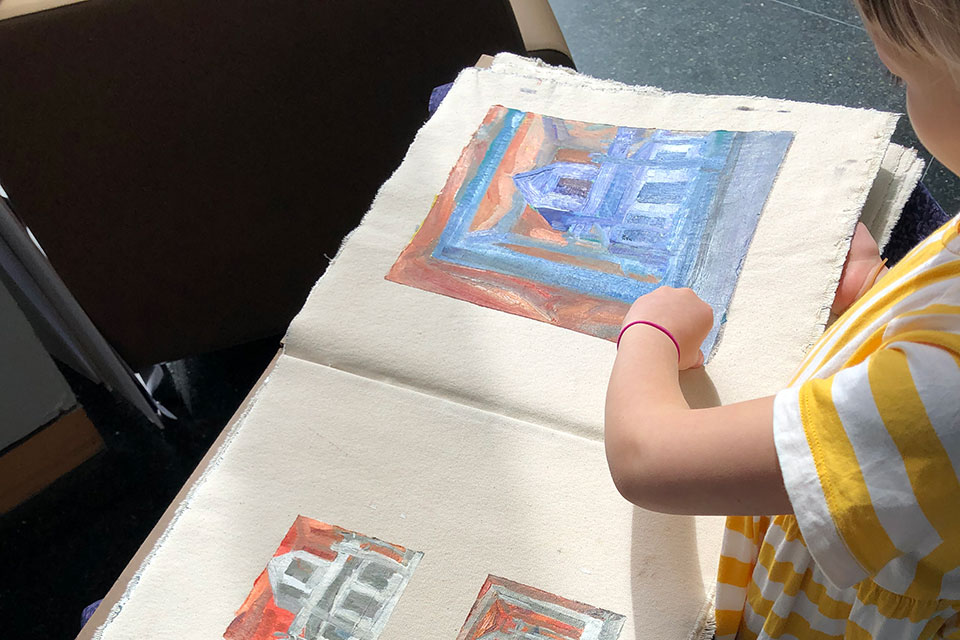 A person looks through a book with paintings in it