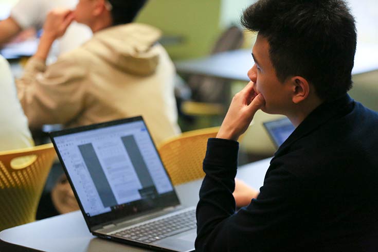 young man with headphones sitting at his laptop and smiling 