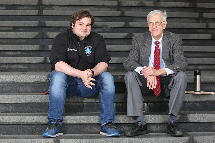 Two people sit on bleachers