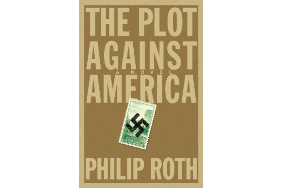 Front cover of "The Plot Against America." Brown background with cream colored letters and a green stamp in the middle with a swastika on it.