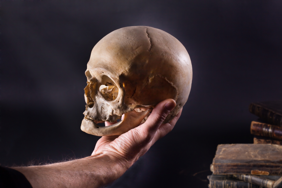 Hand holding a skull, as Hamlet does in Shakespeare's play.