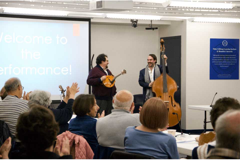 two musicians with a mandolin and an upright bass play in front of a crowd