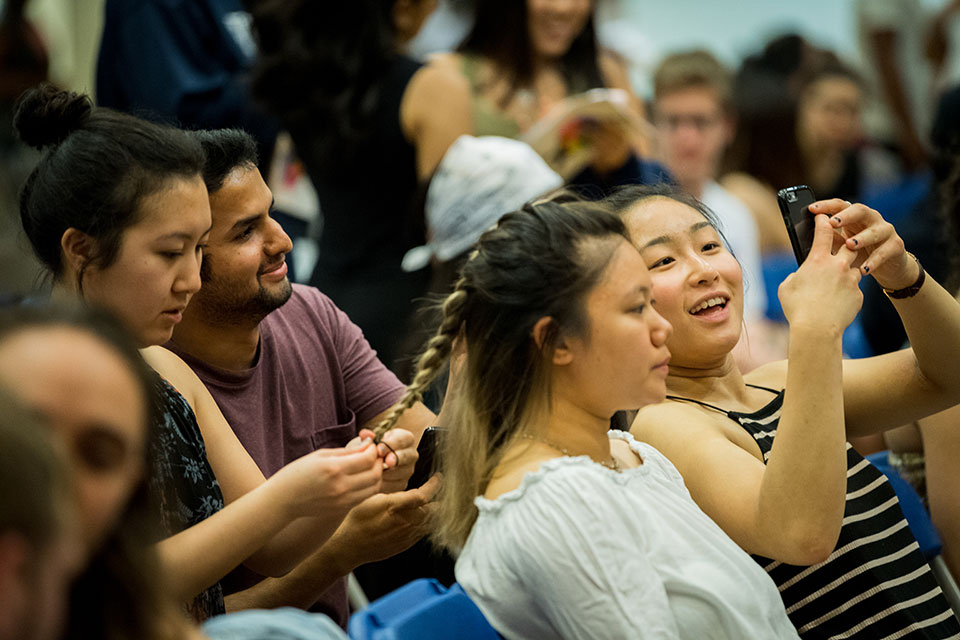 Friends braiding hair and looking at a cell phone