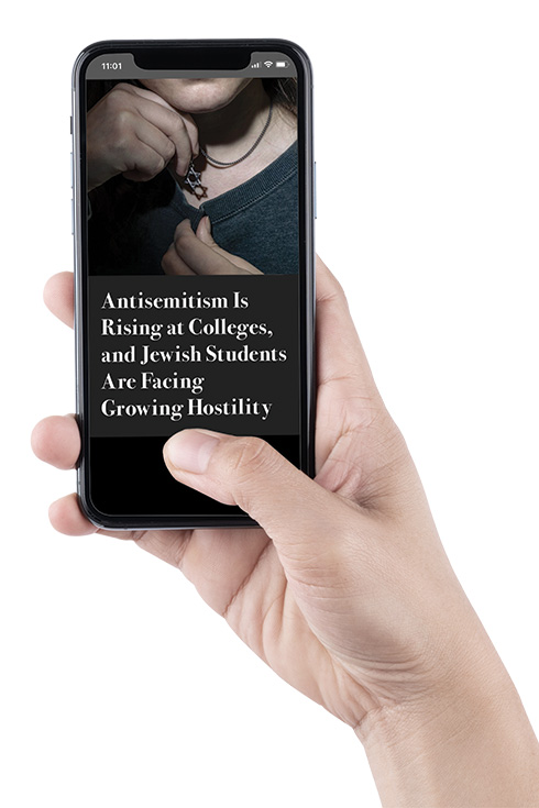 A hand holding a cellphone, on which reads the headline "Antisemitism is Rising at Colleges, and Jewish Students Are Facing Hostility