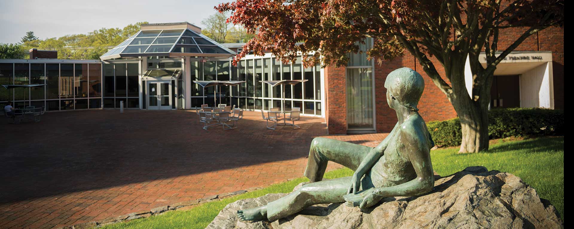 A statue of a person in front of the entrance to Goldfarb Library