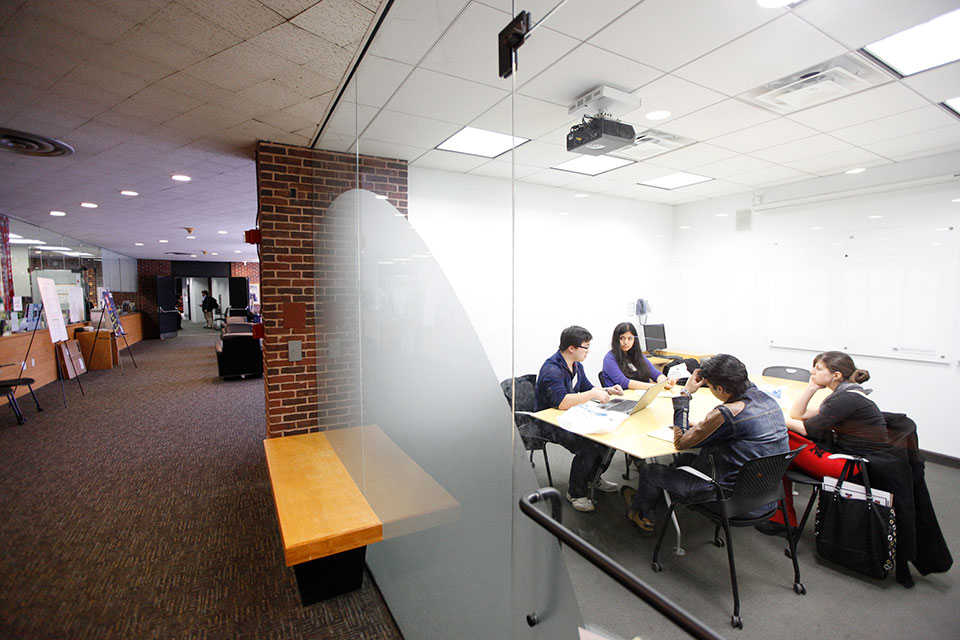 Looking at 4 students at a table through a glass wall