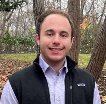 Evan Gandler standing in front of fall foliage