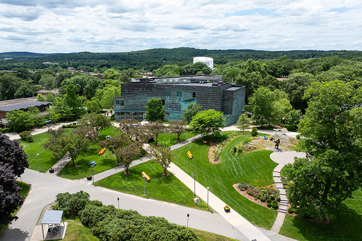 Three people ride through the Brandeis campus on a golf cart.