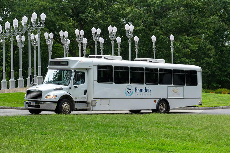 A driver standing next to a Brandeis charter van.
