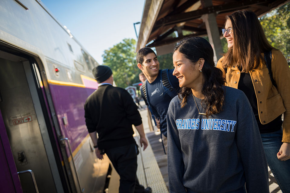Brandeis student walk along the MBTA platform.