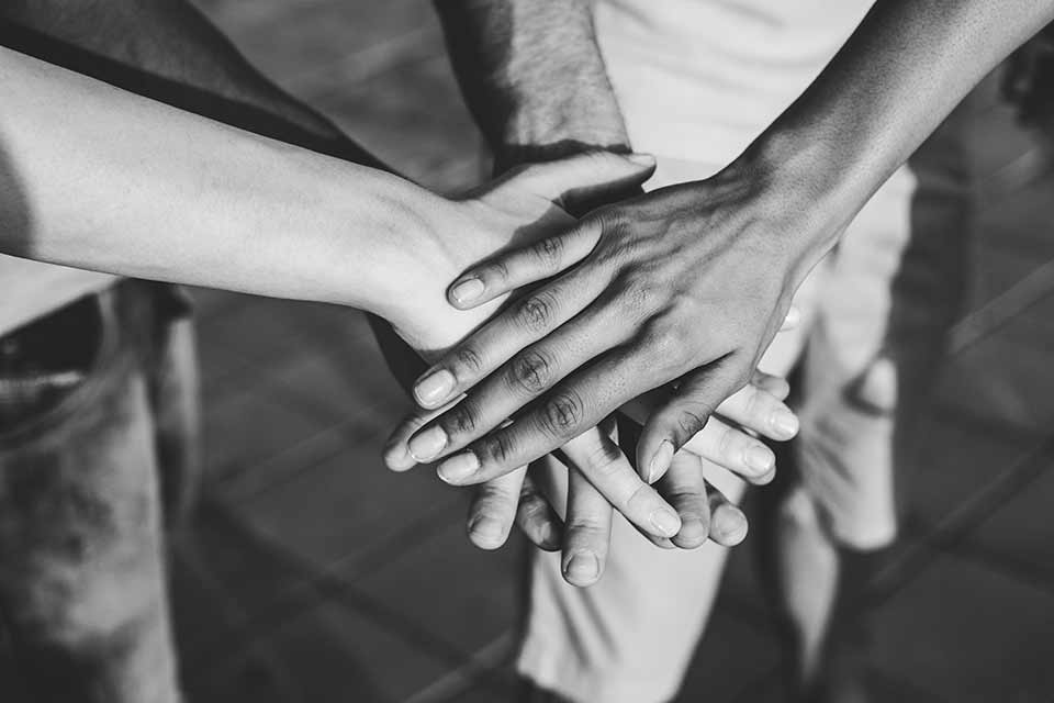 Hands layered on top of one another in black and white