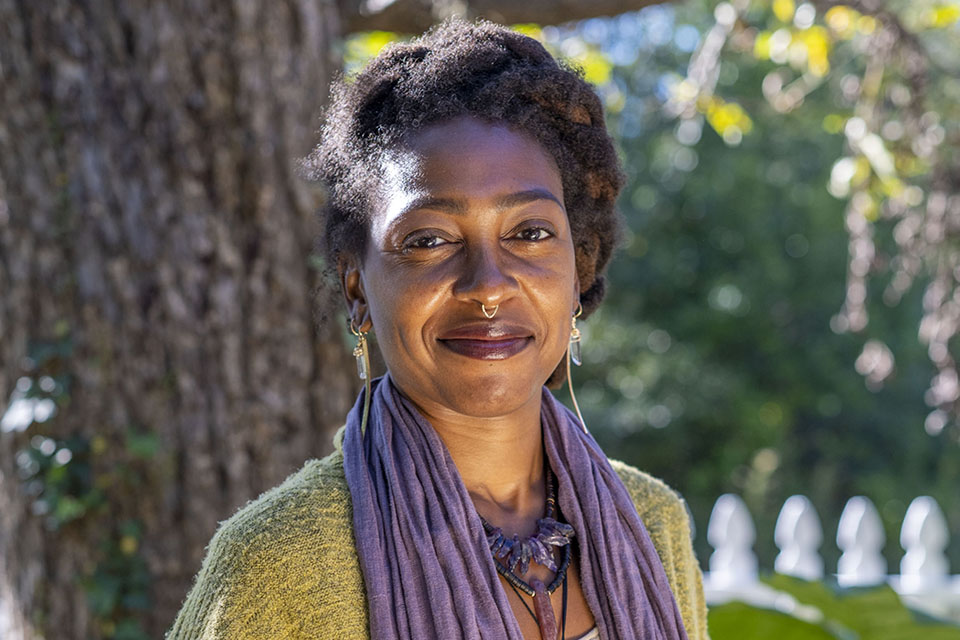 C.Y. standing in front of a tree, smiling, and wearing her handmade jewelry