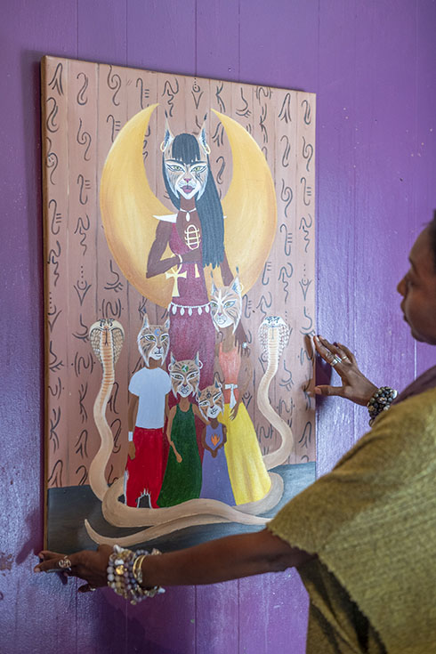 C.Y. hangs a portrait of her family that she painted against a purple wall