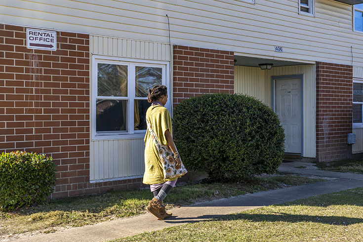 C.Y. walks toward a brick building in the apartment complex she manages