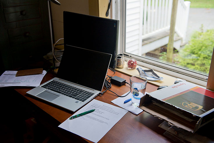 A desk with an open computer facing a window