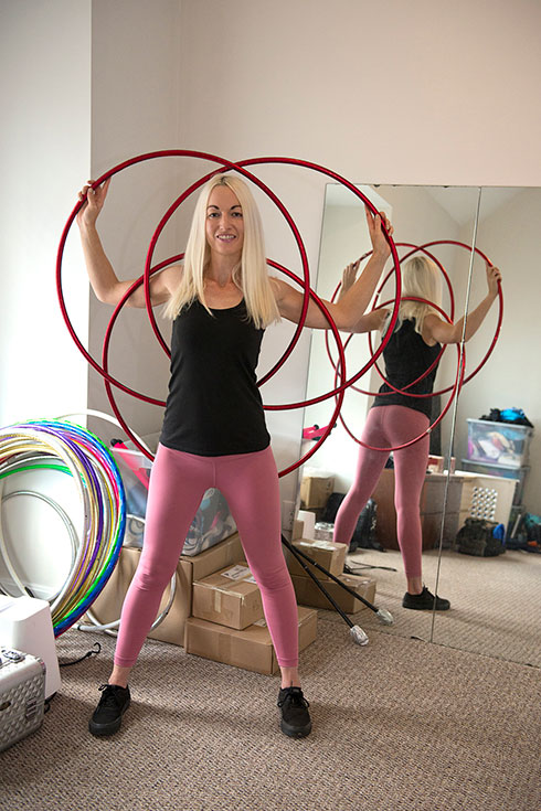 Liz stands with her arms through 3 hula hoops behind her back