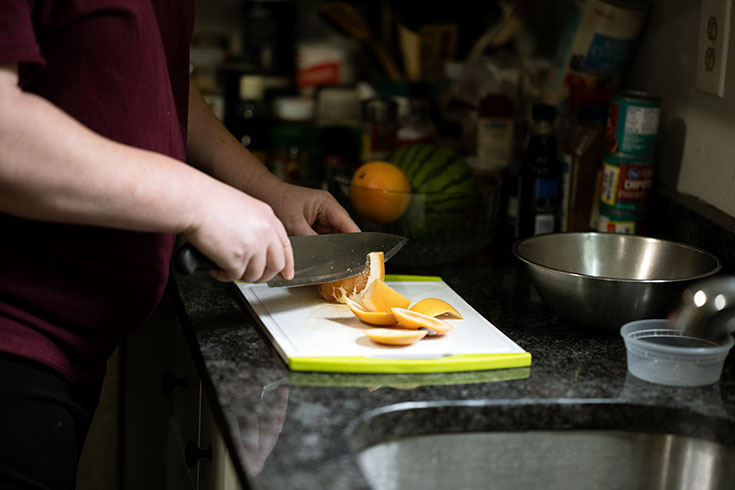 Close up of an orange being cut on a cutting board