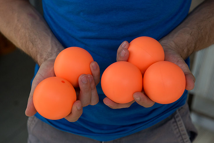 Hands hold bright orange juggling balls