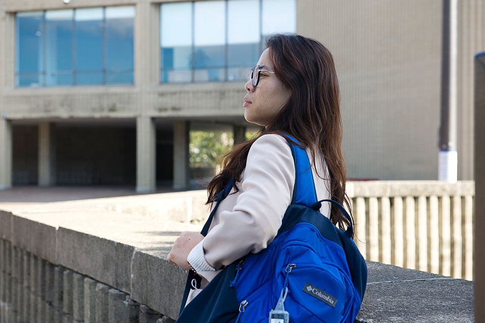 Side profile of Y.L. with a backpack on her back