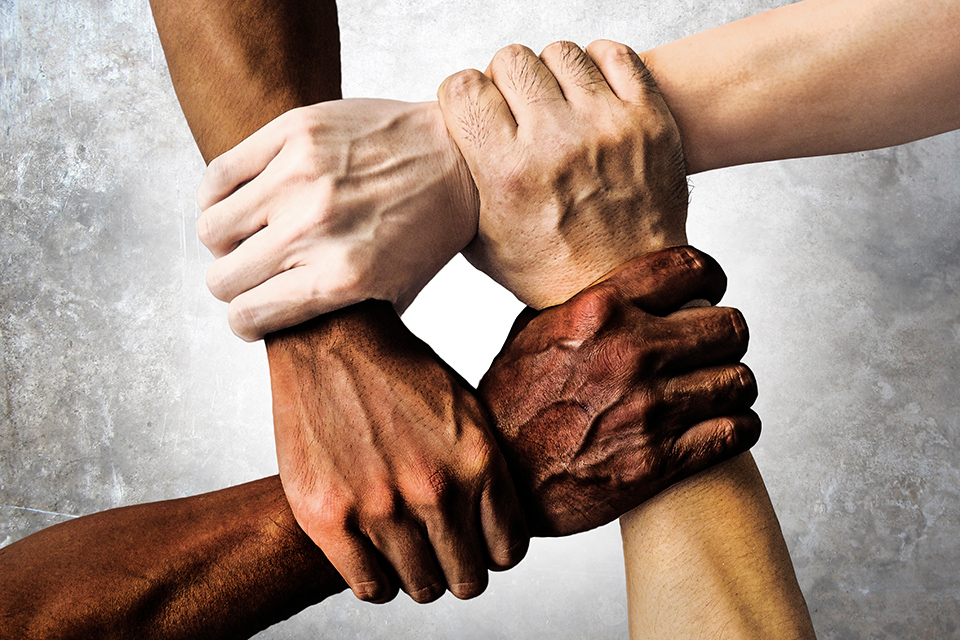 4 hands holding each other of different skin colors