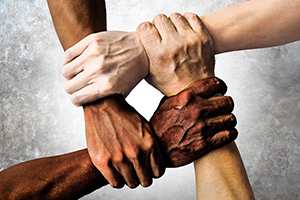Four hands of different colored skin holding on together