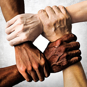 4 hands of different skin tones holding on to each other