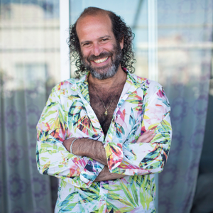 Headshot of Tomer Gardi, smiling, in a floral Hawaiian style shirt.