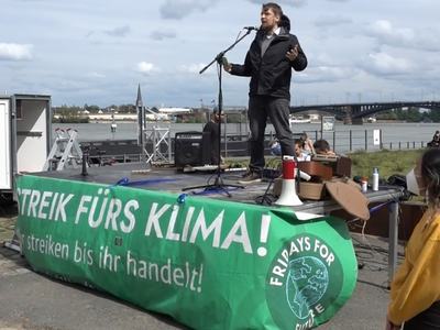 Sebastian Seiffert speaking on a podium at a climate action event.