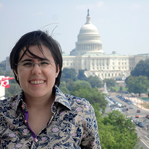 Head shot of Lilly smiling with a building in background