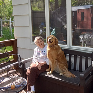 Picture of Doris on a bench with a golden retriever next to her