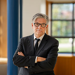 Head shot of Jan with his arms crossed in a suit