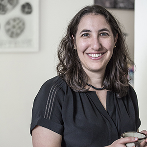 Head shot of Anne Hand smiling holding a coffee mug