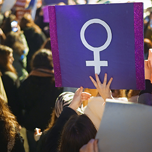 Women at a rally with the image of the female symbol