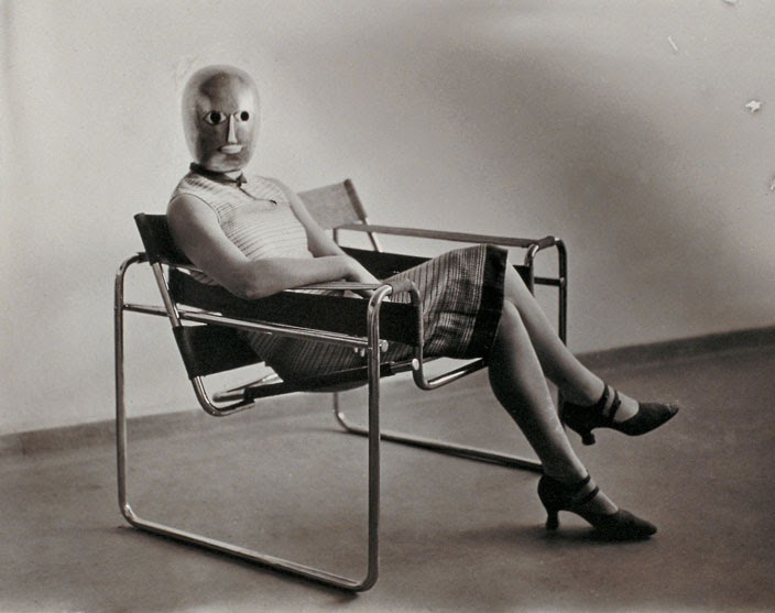 Woman with a Bauhaus mask sitting in a Bauhaus chair