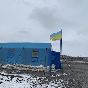Ukrainian flag flying at a blue checkpoint tent.