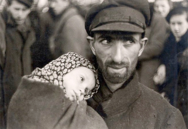 Photograph of a man holding a baby in the Warsaw ghetto